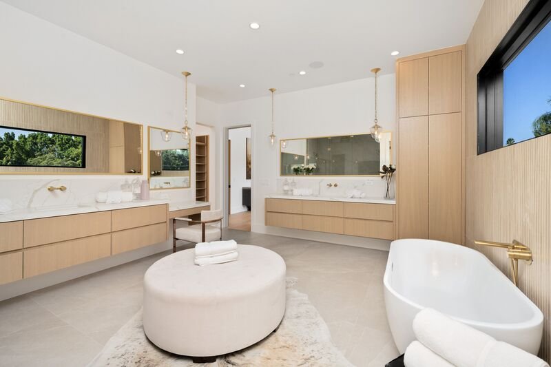 Baño moderno en tonos blanco y aplicaciónes de madera, con tina y espejos largos