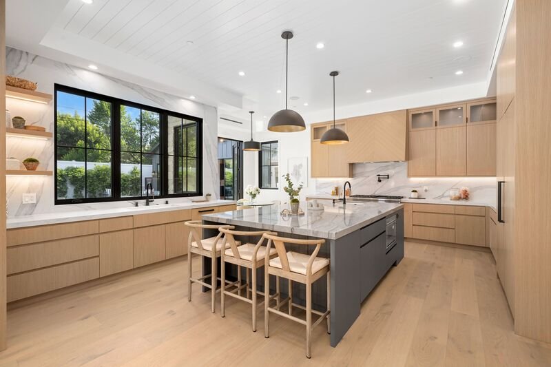 Moderna cocina en tonos beige con gris con una isla en medio con sillas